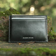 Black leather card holder with 'Hiram Beron' branding on a natural background