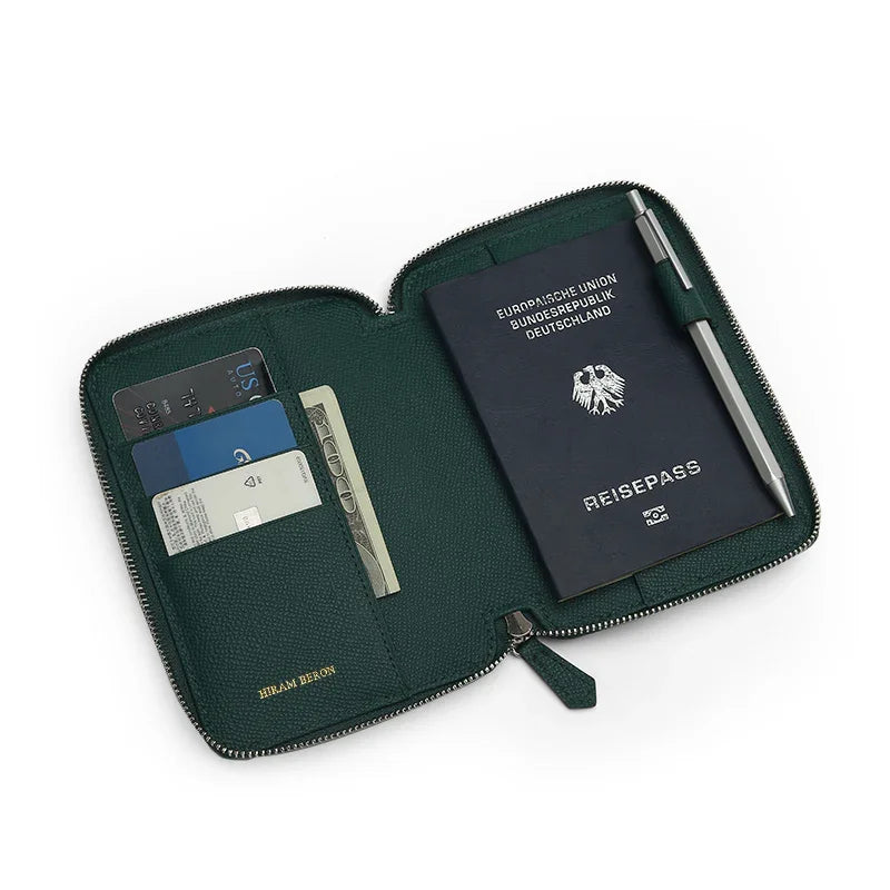 Green epsom leather passport wallet with a passport, card slots, and a pen on a white background