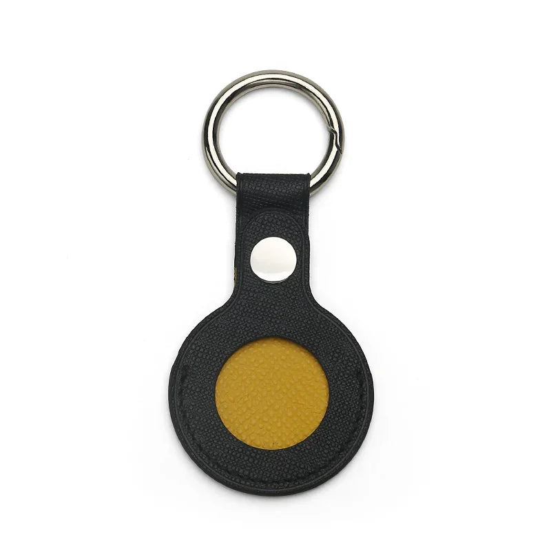 Black saffiano leather airtage keychain with a yellow center on a white background