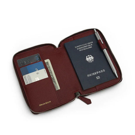 Burgundy epsom leather passport wallet with passport, cards, and pen on a white background