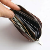 Brown leather coin wallet with cards held open by a hand on a white background