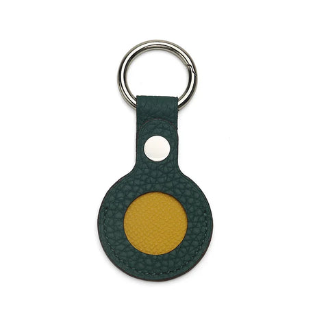 Green leather airtag holder and yellow round keychain with a silver ring on a white background