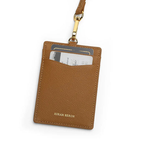 Brown leather cardholder with gold lanyard on a white background