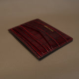 burgundy leather cardholder on a beige surface