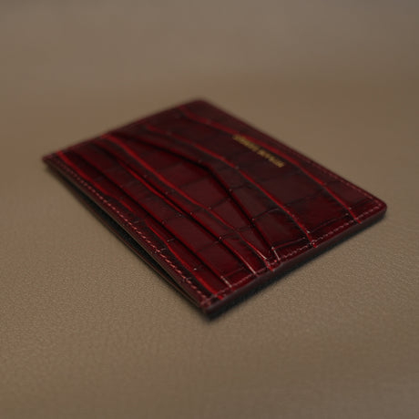burgundy leather cardholder on a beige surface