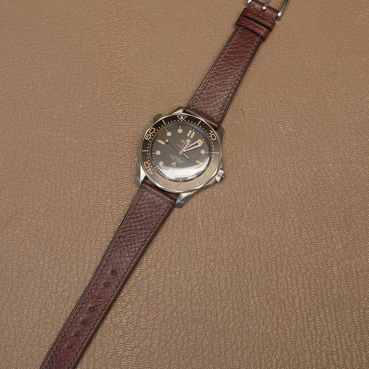 Complete brown Italian Badalassi veg-tan leather watch strap mounted on luxury sports watch on leather desk pad