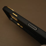 Close-up of a black phone case with gold accents on a brown textured surface