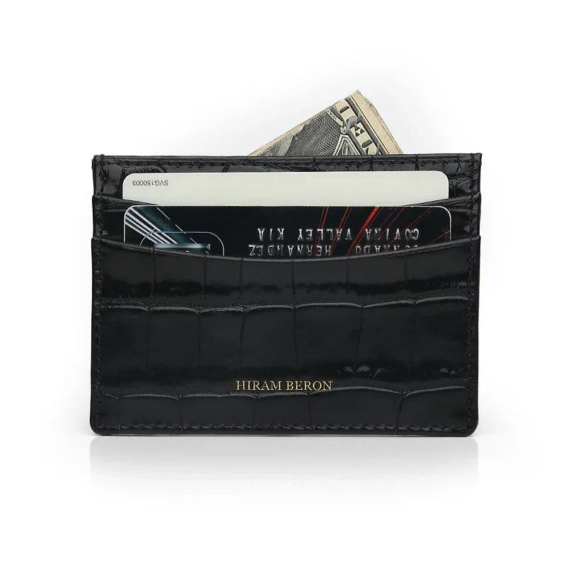 Black crocodile-patterned calfskin card holder with cards and money on a white background