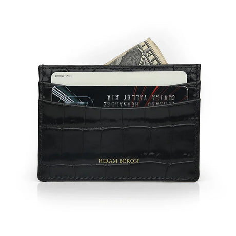 Black crocodile-patterned calfskin card holder with cards and money on a white background