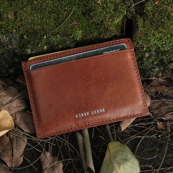 Brown leather card case with 'HIRAM BERON' branding on a natural background