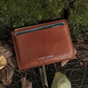 Brown leather card case with 'HIRAM BERON' branding on a natural background