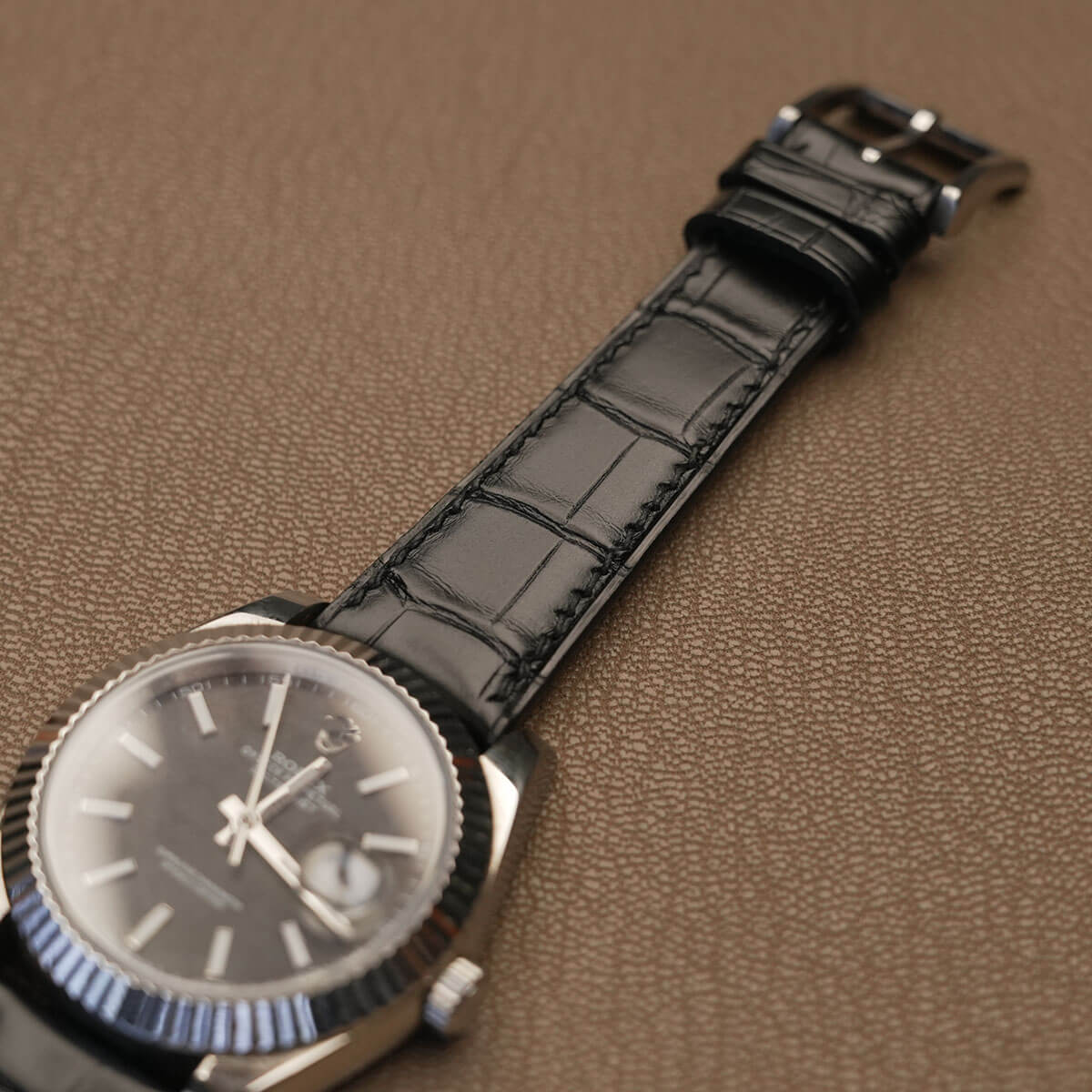 Macro view of raised padded lug contour and square scale pattern on genuine black alligator watch strap 