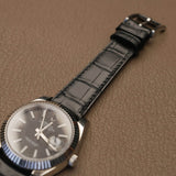 Macro view of raised padded lug contour and square scale pattern on genuine black alligator watch strap 
