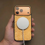 iPhone 17 pro case with gold python skin and magsafe charging held by a hand against a brown background