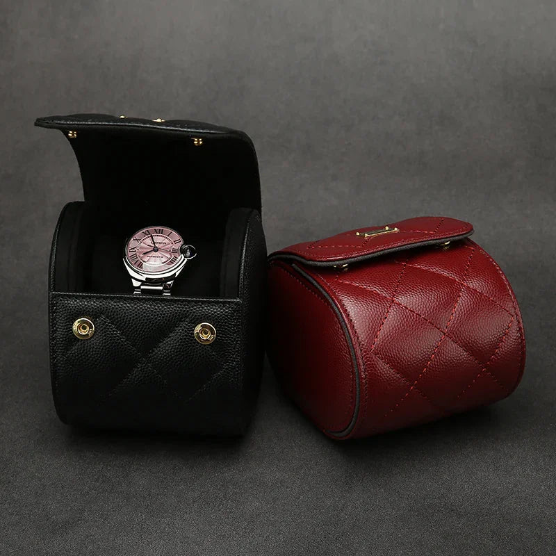 Black and red leather watch roll case with a watch inside on a gray background