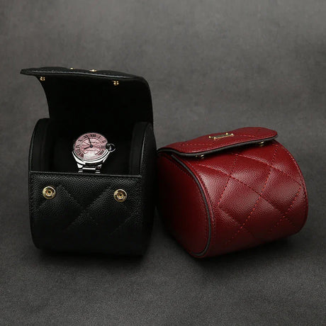 Black and red leather watch roll case with a watch inside on a gray background