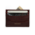 Slim Burgundy crocodile-patterned calfskin cardholder with cards and money on a white background