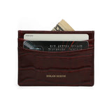 Slim Burgundy crocodile-patterned calfskin cardholder with cards and money on a white background