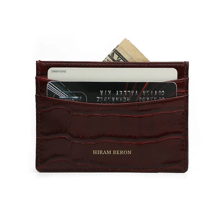 Slim Burgundy crocodile-patterned calfskin cardholder with cards and money on a white background