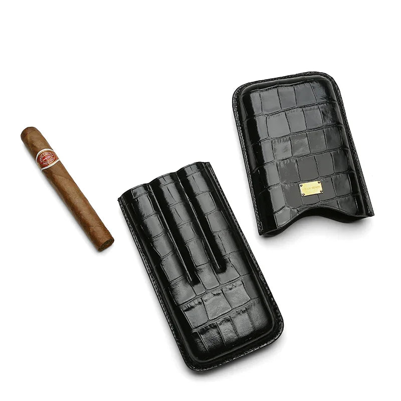 Luxury black crocodile leather cigar case with gold plaque, shown with premium cigar