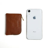 Brown leather coin pouch next to a white iPhone on a white background
