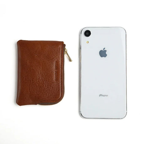 Brown leather coin pouch next to a white iPhone on a white background