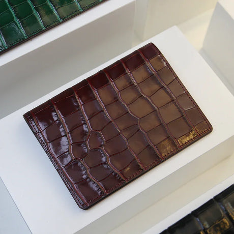 Burgundy crocodile-patterned leather passport wallet on a white surface