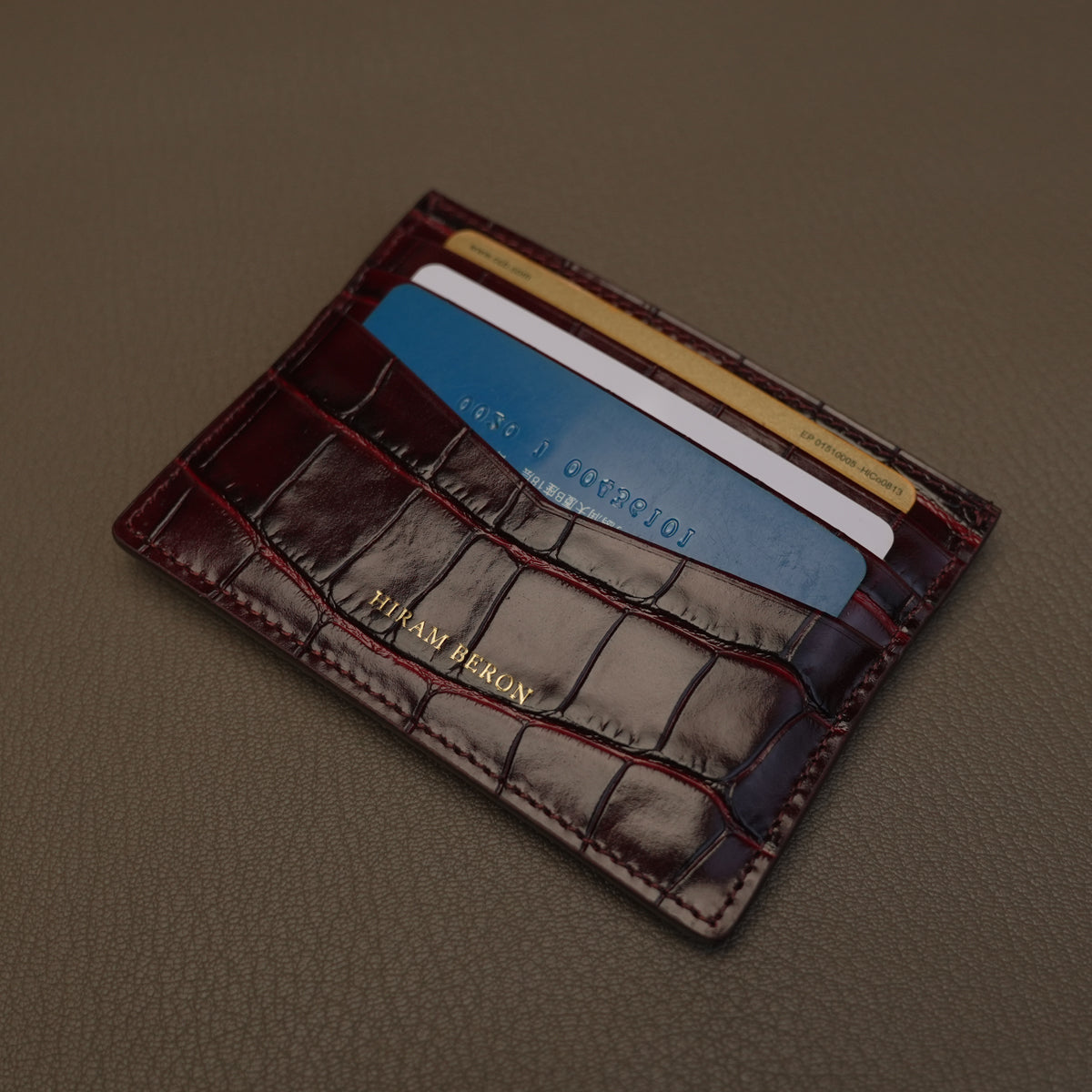 burgundy leather cardholder with cards on a brown background