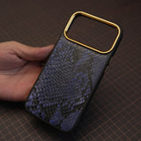 Hand holding a phone case with genuine python skin on a grid background