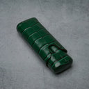 Emerald green croc-embossed leather cigar case with strap closure on textured gray surface
