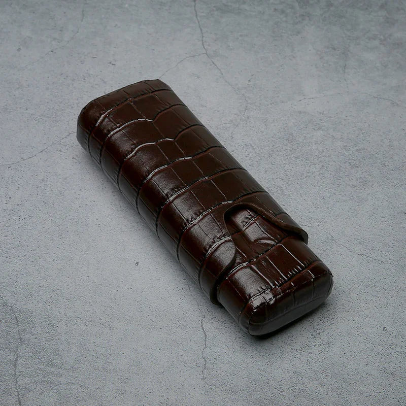 Luxury brown crocodile-textured leather cigar case on concrete surface