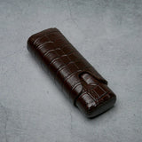 Luxury brown crocodile-textured leather cigar case on concrete surface