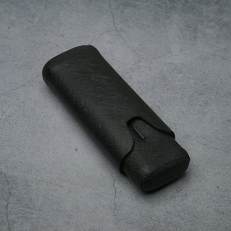 Black textured leather eyeglass case on concrete surface, luxury accessory for men