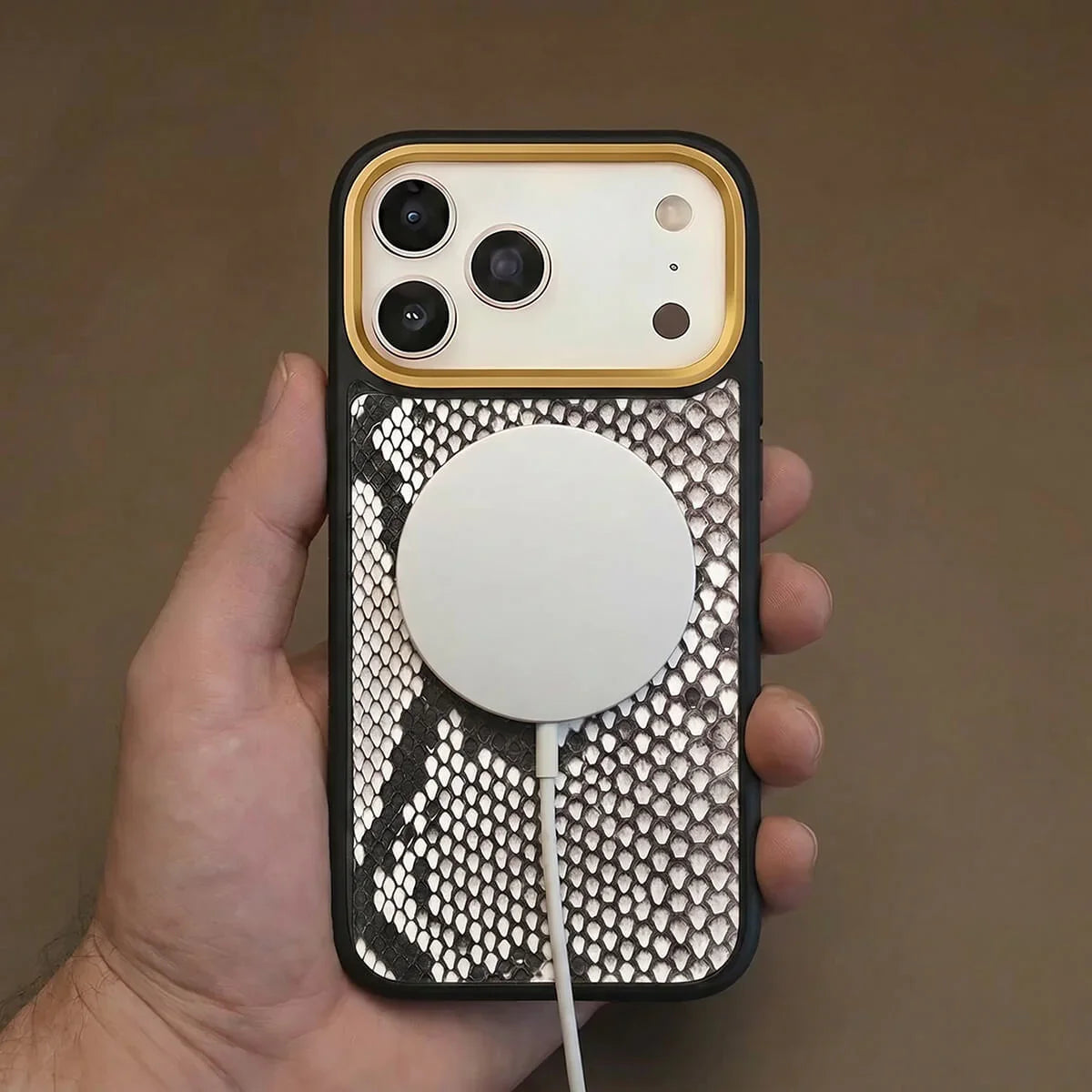 iPhone 17 pro case with snake skin and magsafe charging held by a hand against a brown background