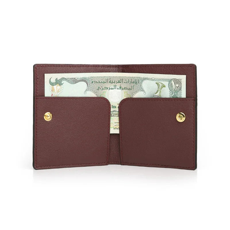 burgundy leather wallet with gold buttons holding a banknote on a white background