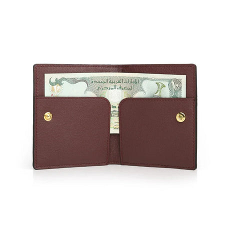 burgundy leather wallet with gold buttons holding a banknote on a white background
