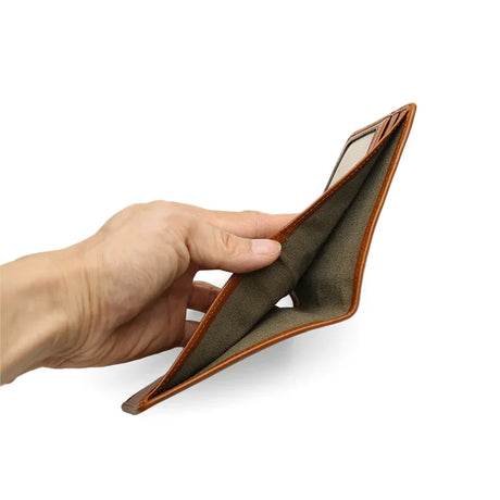 Hand holding a brown leather wallet on a white background