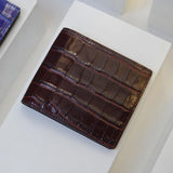 Burgundy crocodile pattern leather wallet on a white surface