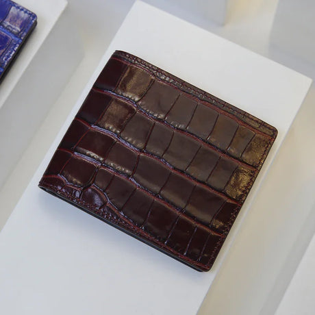 Burgundy crocodile pattern leather wallet on a white surface