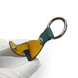 Leather airtag keychain holder with a unique design held by a white glove on a light background