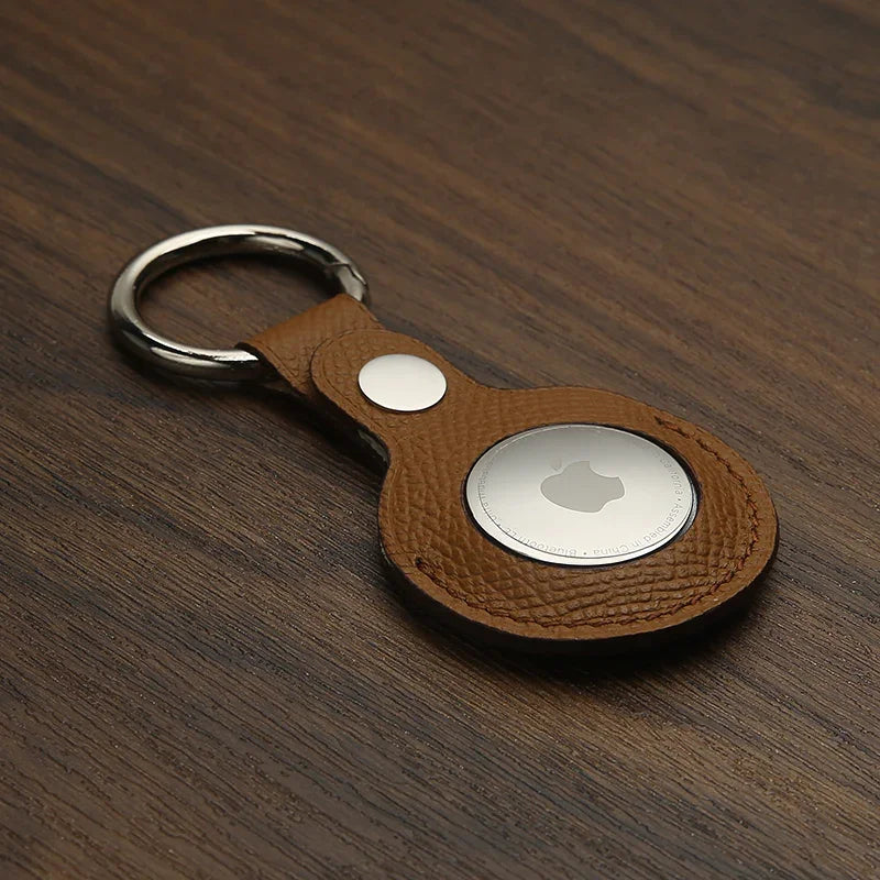 Brown epsom leather airtag keychain on a wooden surface