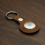 Brown epsom leather airtag keychain on a wooden surface