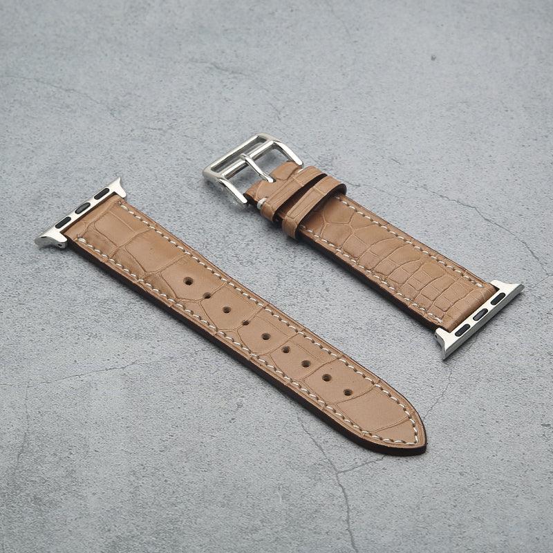 Poussier crocodile skin watch strap with silver buckle on a gray surface