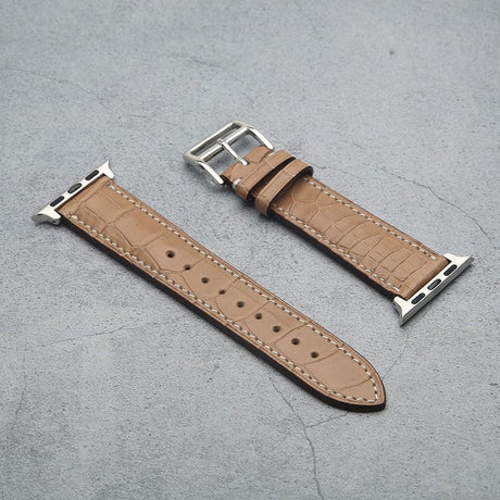 Poussier crocodile skin watch strap with silver buckle on a gray surface