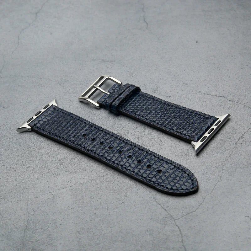 navy blue lizard skin watch strap with silver buckle on a gray surface