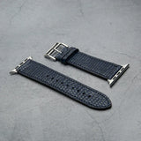 navy blue lizard skin watch strap with silver buckle on a gray surface