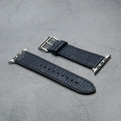 navy blue lizard skin watch strap with silver buckle on a gray surface