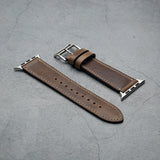 Brown leather watch strap with silver metal clasp on a gray surface
