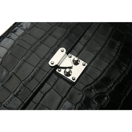 Close-up of a black crocodile-patterned leather bag with a silver clasp.