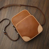 Brown leather reporter bag on a wooden surface